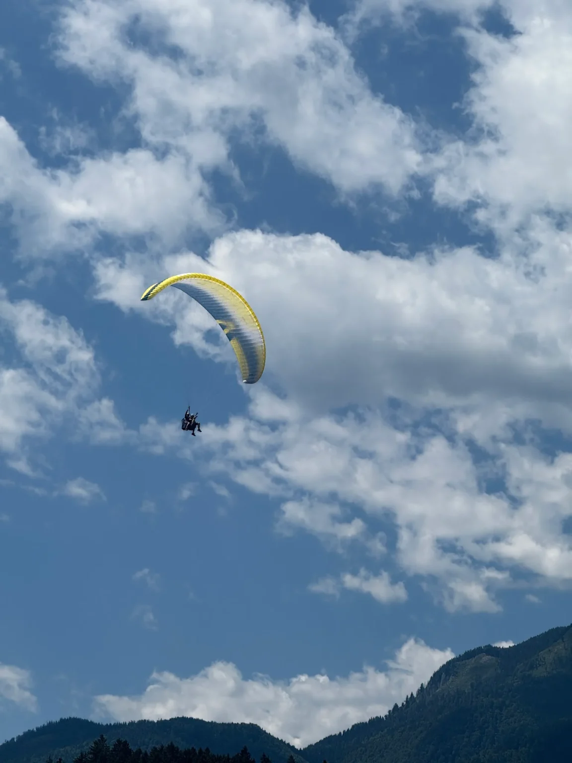 Tandemsko jadralno padalo med oblaki nad gorami